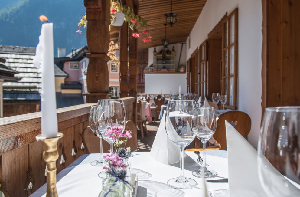 Schön gedeckte Tische auf dem Balkon im Restaurant Seewirt Zauner mit Blick auf Hallstatt und die umliegenden Berge des Salzkammergutes