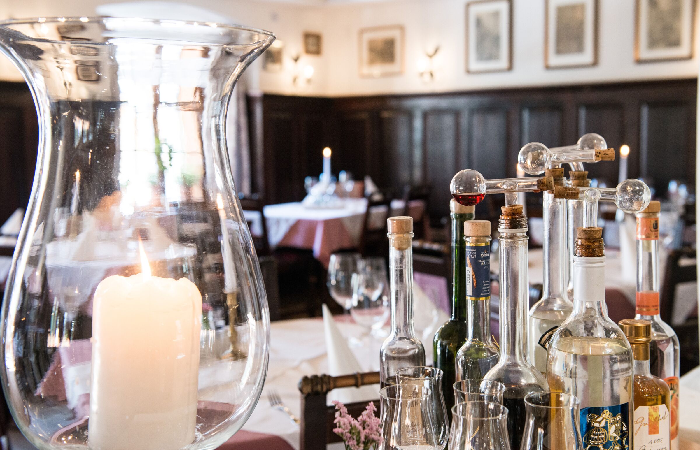 Restaurant im Seewirt Zauner mit schön gedeckten Tischen und brennenden Kerzen sowie einer Auswahl an vielen alkoholischen Getränken
