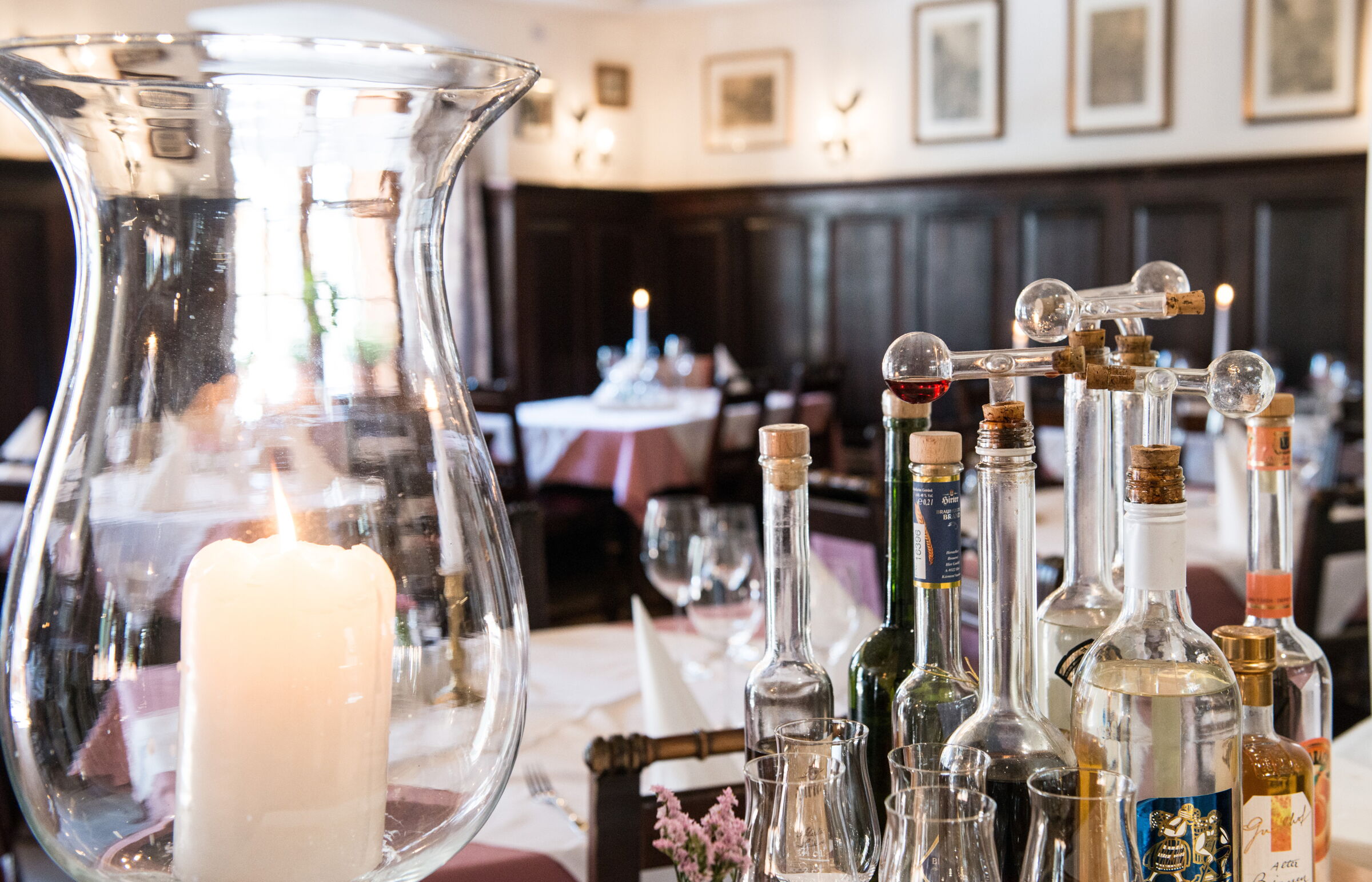 Restaurant im Seewirt Zauner mit schön gedeckten Tischen und brennenden Kerzen sowie einer Auswahl an vielen alkoholischen Getränken