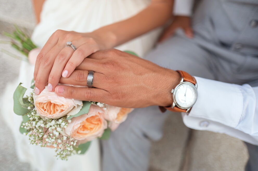 Bridal couple hand in hand with a bouquet