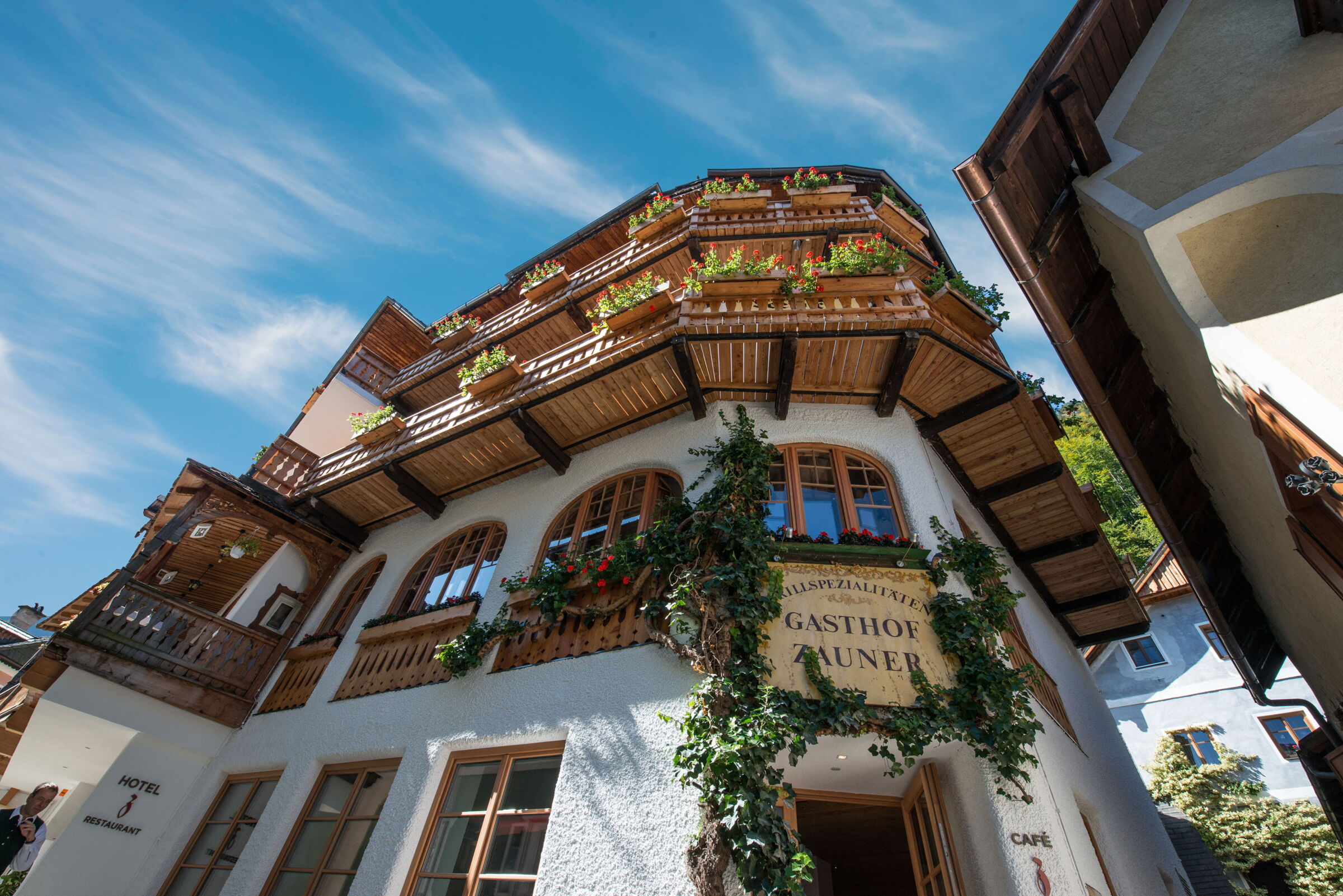 Außenansicht des Hotels Seewirt Zauner mit rot blühenden Balkonblumen im Zentrum des UNESCO-Weltkulturerbes Hallstatt